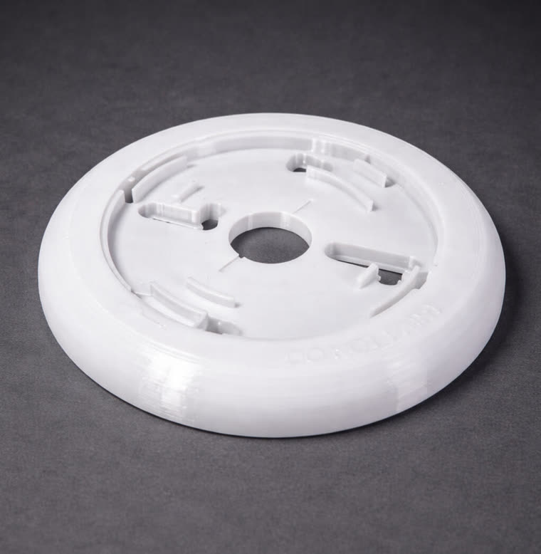 Base circular blanca para sensor de humo, con alojamientos de montaje y la leyenda DO NOT PAINT en relieve